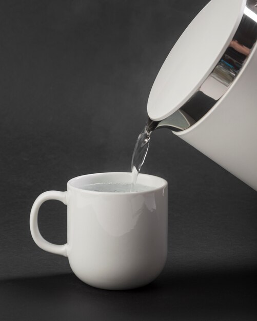 Electric kettle pouring water in cup