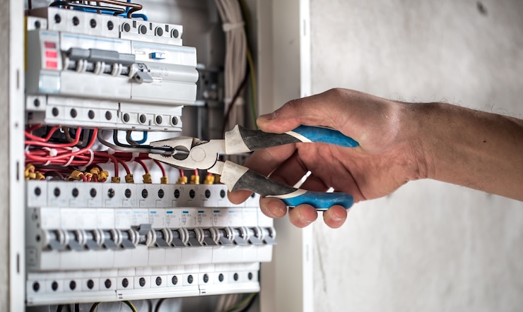 Free Photo an electrical technician working in a switchboard with fuses