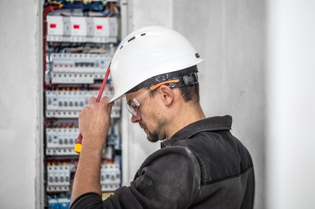 Electrical technician working in a switchboard with fuses