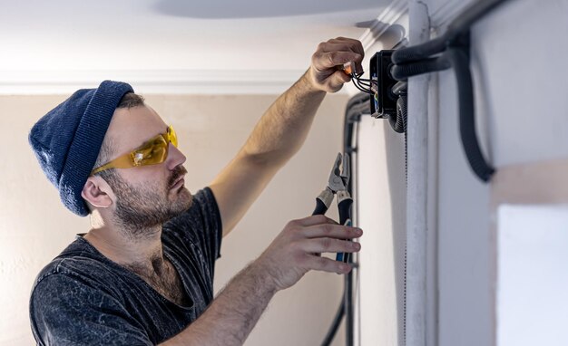 An electrician is mounting electric sockets on the white wall indoors