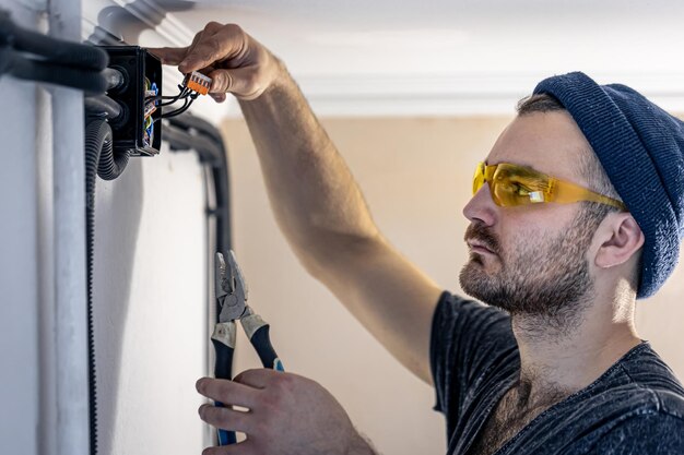 An electrician is mounting electric sockets on the white wall indoors