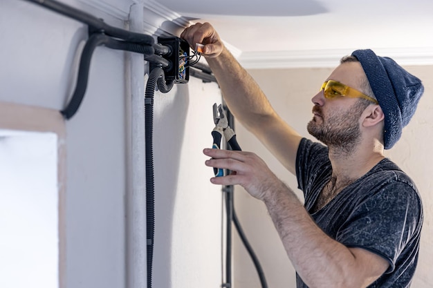 An electrician is mounting electric sockets on the white wall indoors