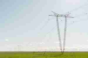Foto gratuita torri di elettricità in fila nel mezzo di un campo agricolo con cielo sereno