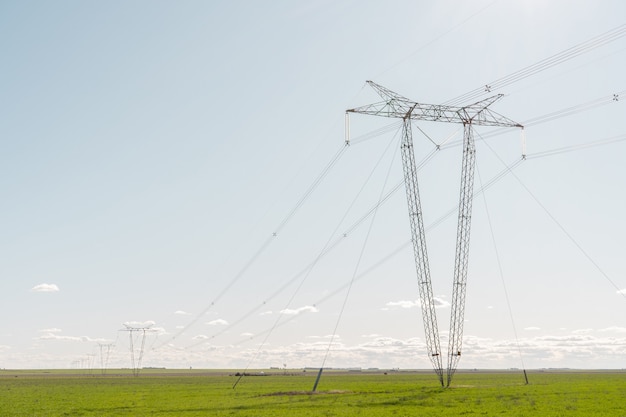 澄んだ空の農地の真ん中に一列に並ぶ電気の塔