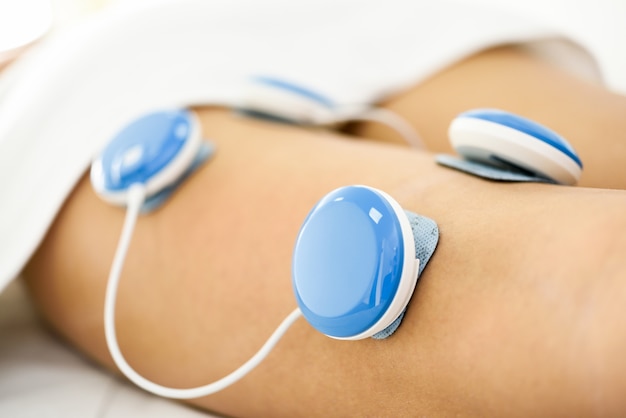 Electro stimulation in physical therapy to a young woman leg.