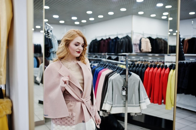 毛皮のコートと革のジャケットの店でコートを着た優雅なブロンドの女の子