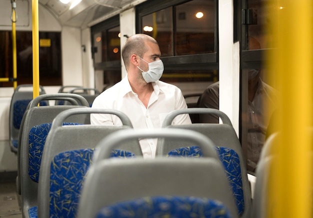 Free photo elegant adult male riding bus with medical mask