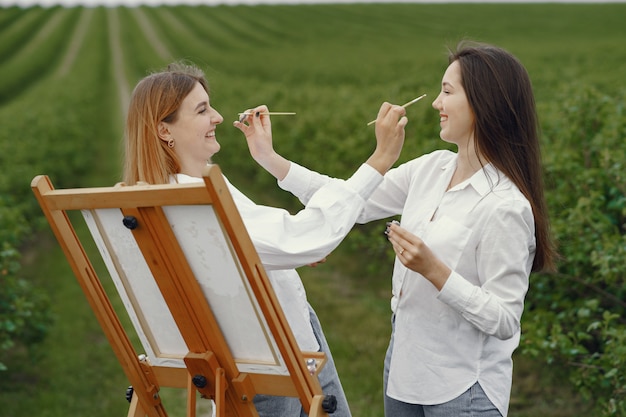 Бесплатное фото Элегантные и красивые девушки рисуют в поле