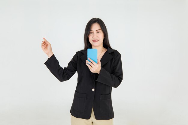 Элегантная азиатская бизнесвумен читает счастливое сообщение с мобильного телефона и улыбается, чтобы показать пальцем, чтобы объяснить удивительную рекламную кампанию и интересное уведомление как руководство для прекрасного варианта работы.