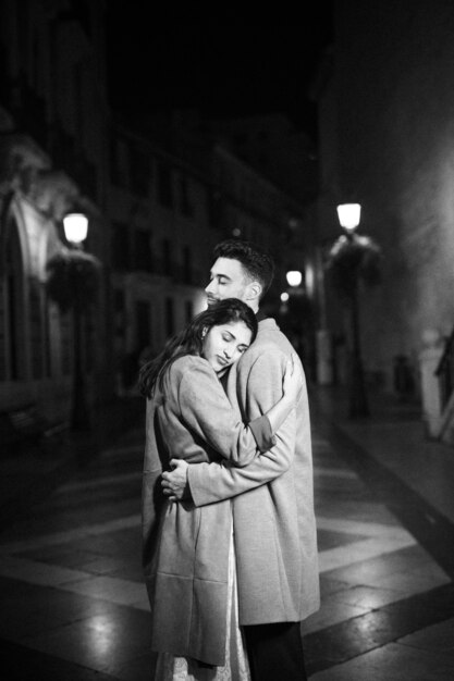 Elegant attractive woman hugging with young man on street at night