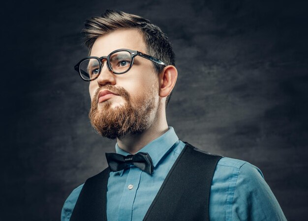 Элегантный бородатый мужчина-хипстер, одетый в синюю рубашку и жилет на сером фоне виньетки.