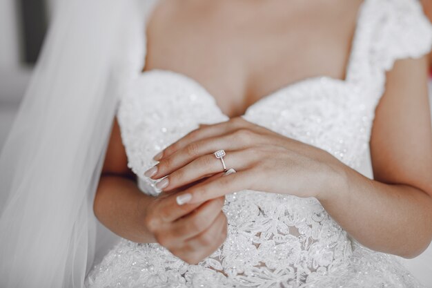 A elegant and beautiful bride at home standing near window 