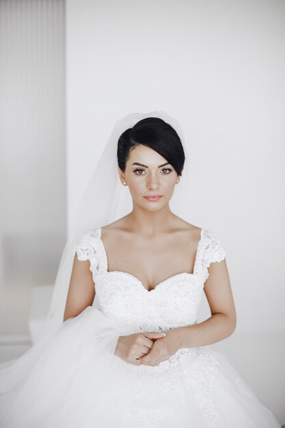 A elegant and beautiful bride at home standing near window 