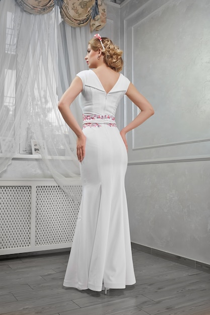 Elegant, beautiful, fashionable woman blonde in a long white dre
