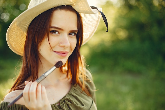 Elegant and beautiful girl painting in a field