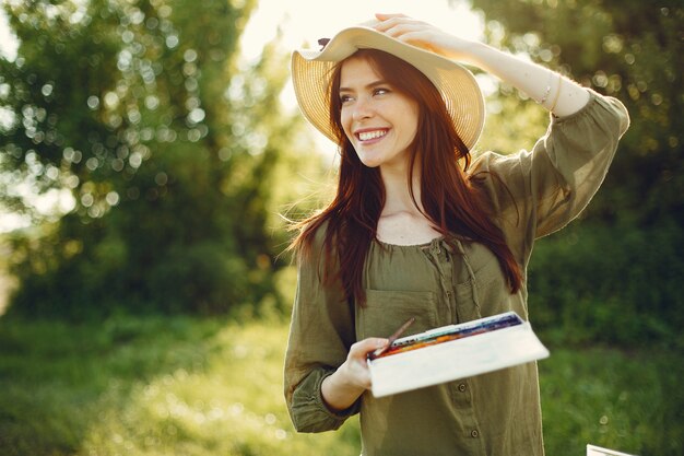 Elegant and beautiful girl painting in a field