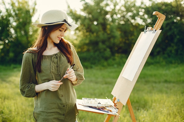 Elegant and beautiful girl painting in a field