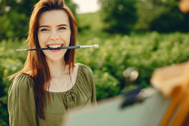 Elegant and beautiful girl painting in a field