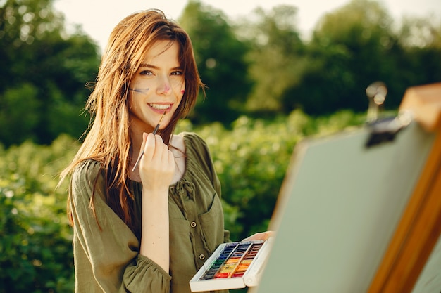 Elegant and beautiful girl painting in a field