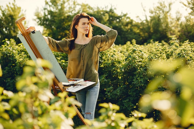 Foto gratuita ragazza elegante e bella pittura in un campo