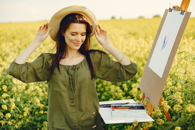 Elegant and beautiful girl painting in a field