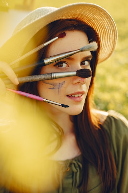 Free photo elegant and beautiful girl painting in a field