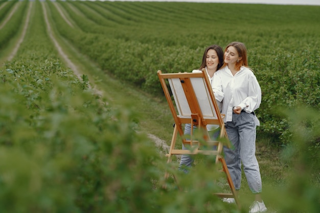 Elegant and beautiful girls painting in a field