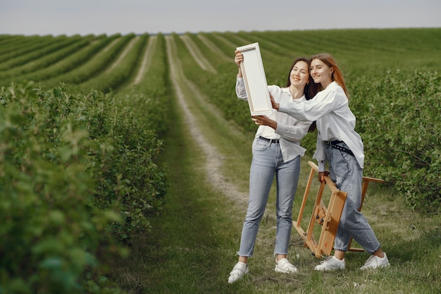 Elegant and beautiful girls painting in a field