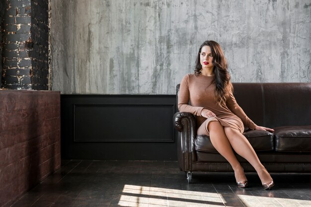 Elegant beautiful young woman sitting on sofa