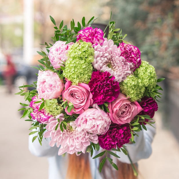 An elegant bouquet of pink and purple flowers with decorative green leaves