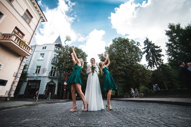 Elegant bridesmaids with bride throwing bouquets