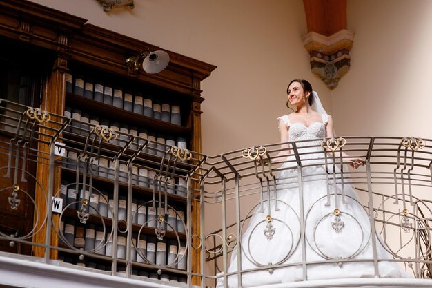屋内のバルコニーに立っているエレガントなブルネットの花嫁
