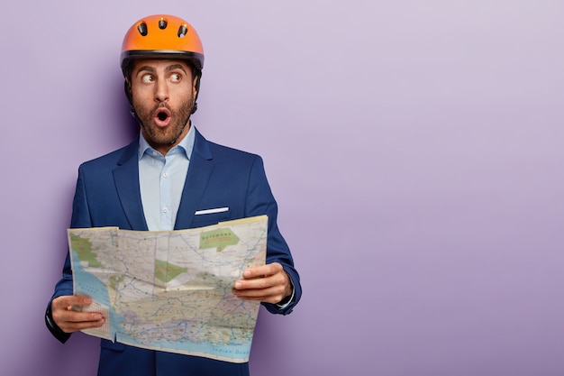 Free photo elegant businessman posing in classy suit and red helmet at the office