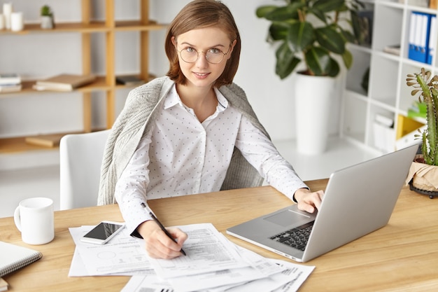 Elegant businesswoman dressed formally sitting with laptop