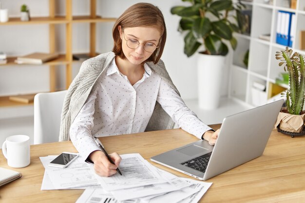 Elegant businesswoman dressed formally sitting with laptop