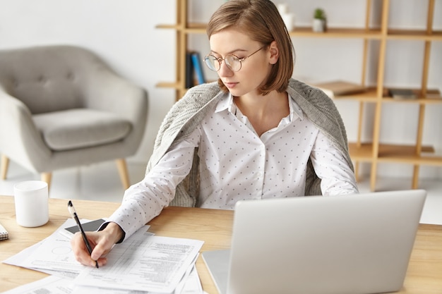 Elegant businesswoman dressed formally sitting with laptop