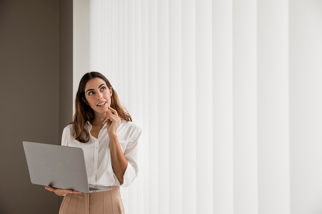 Бесплатное фото Элегантная деловая женщина, использующая ноутбук с копией пространства