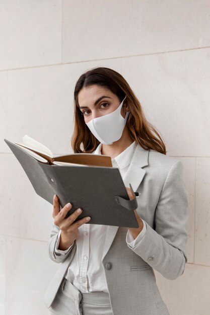 Free photo elegant businesswoman with mask and agenda