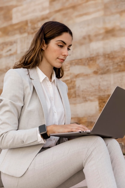 Elegant businesswoman with smartwatch working on laptop