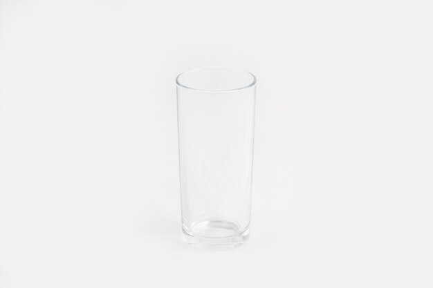 白い壁に分離されたエレガントな透明なガラスカップ
