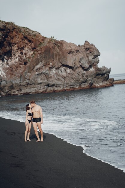 Elegant couple on a beach near rocks