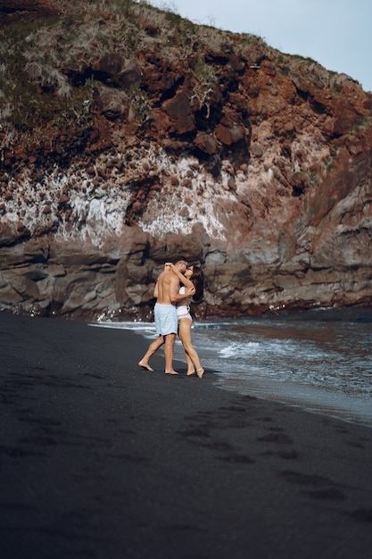 Elegant couple on a beach near rocks