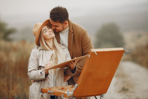 Elegant couple painting in a autumn field