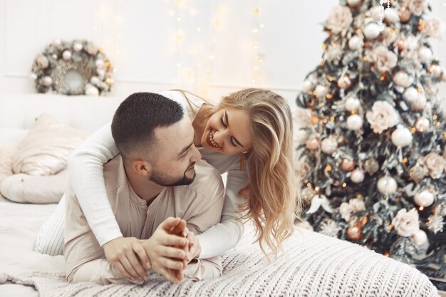 クリスマスの装飾のベッドに座っているエレガントなカップル