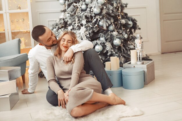 Elegant couple sitting at home near christmas tree