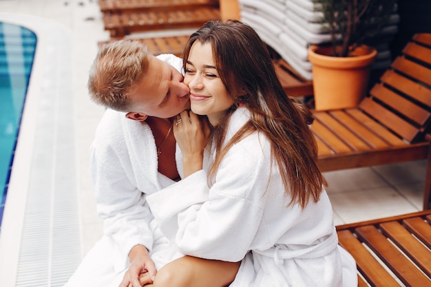 Free photo elegant couple sitting near a swimmingpool