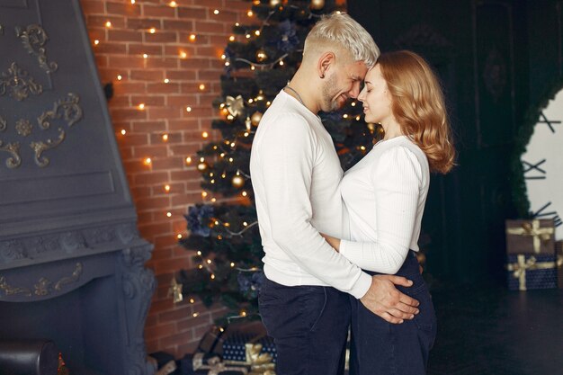 Elegant couple standing at home near christmas tree