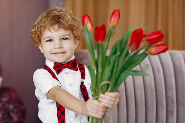 Free photo elegant cute little boy with bouquet of tulip