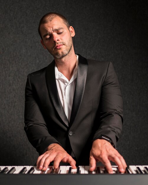 Элегантно одетый музыкант, играющий на клавишных, средний план