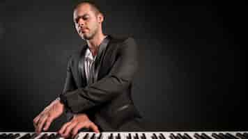 Free photo elegant dressed musician playing keyboards